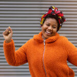 Happy young woman dancing in front of a wall