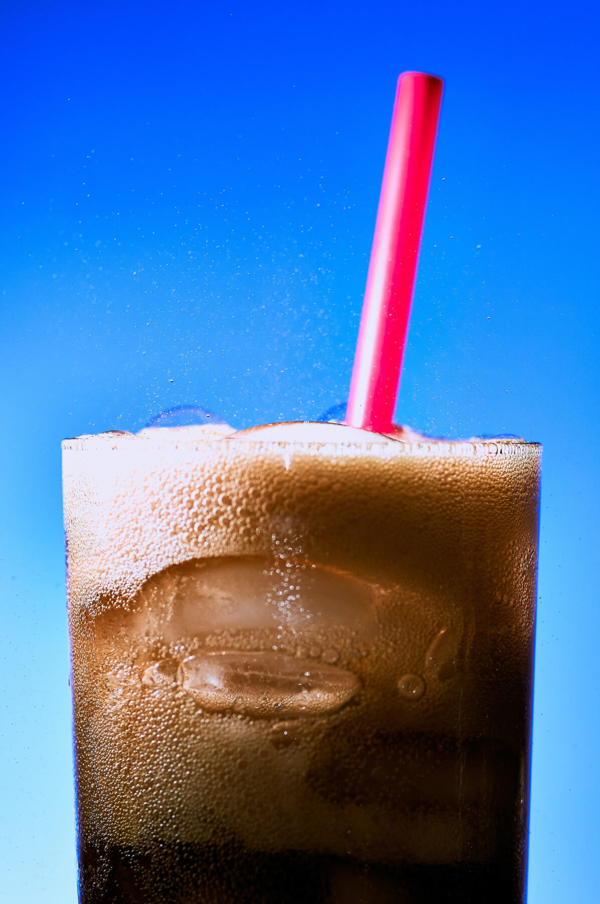 Cola drink in a glass with a straw