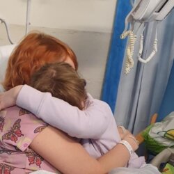 Woman in hospital bed hugging her child