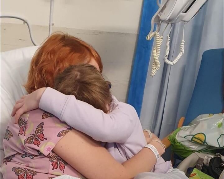 Woman in hospital bed hugging her child