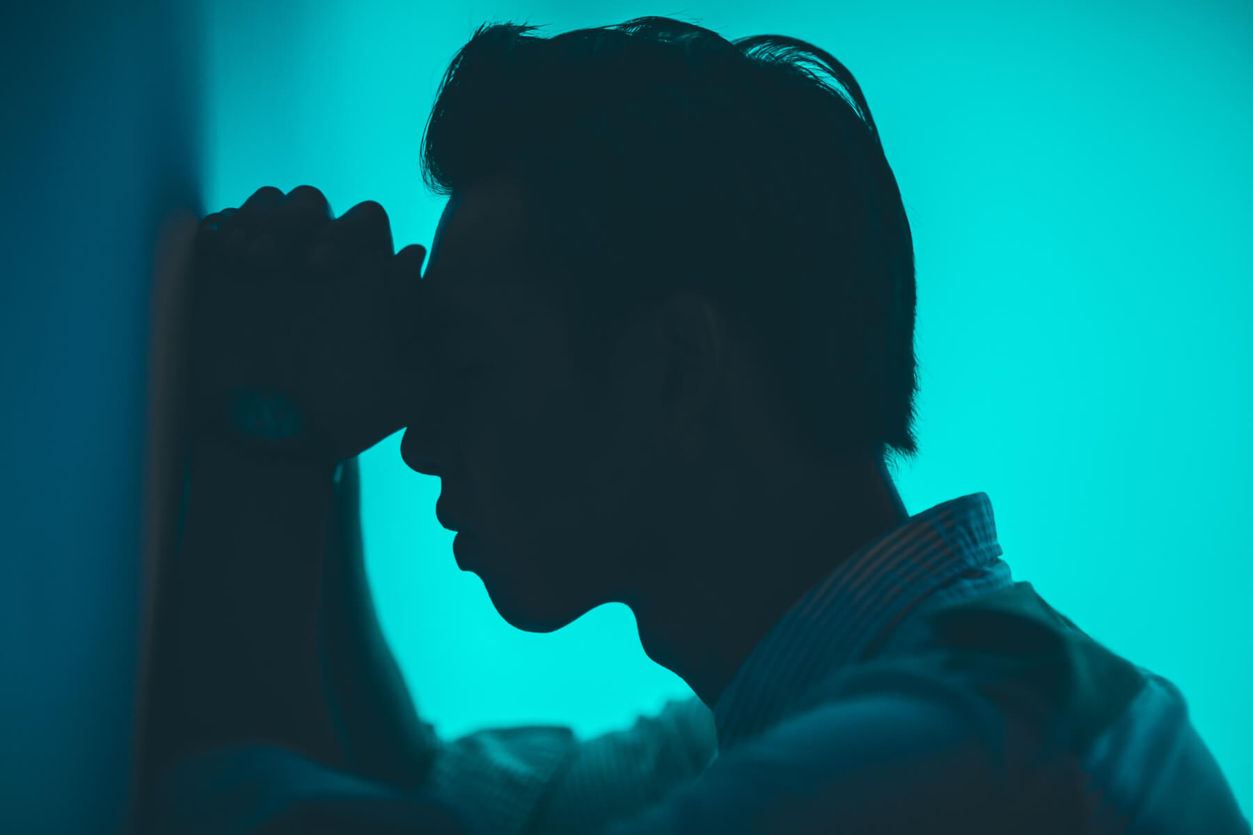 Man in silhouette against a cyan background